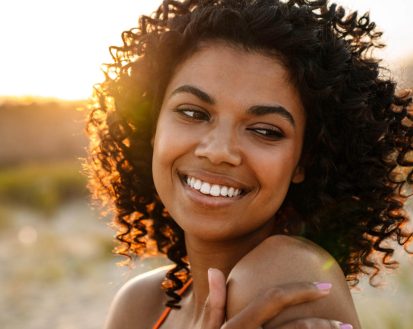 smiling-young-african-woman-walking-at-the-beach-2025-02-16-08-47-14-utc.jpg